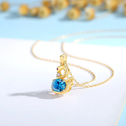 Pendentif cygne topaze radieuse en or jaune 18K orné d'un rubis éclatant et d'un diamant vue de côté.