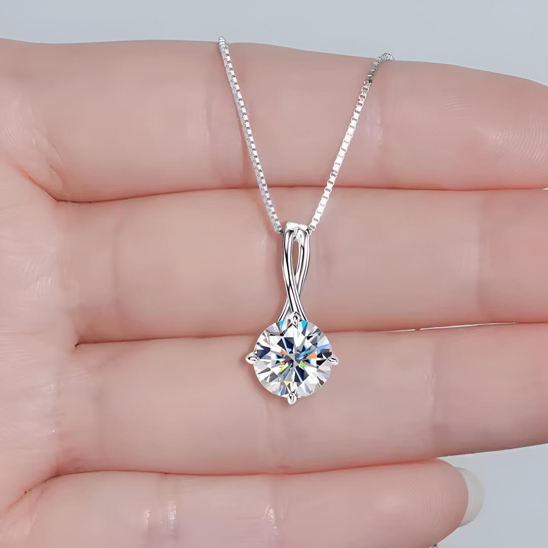 Pendentif echevêtré en argent 925 plaqué or blanc discret et moissanite solitaire sur une main vue de proche.
