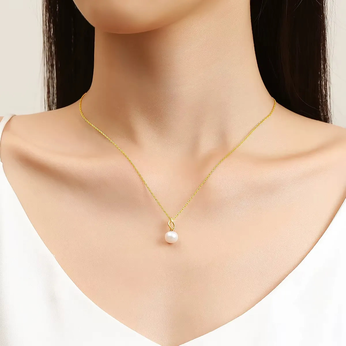 Pendentif flamme en or jaune et perle nacrée porté au cou d'une femme.
