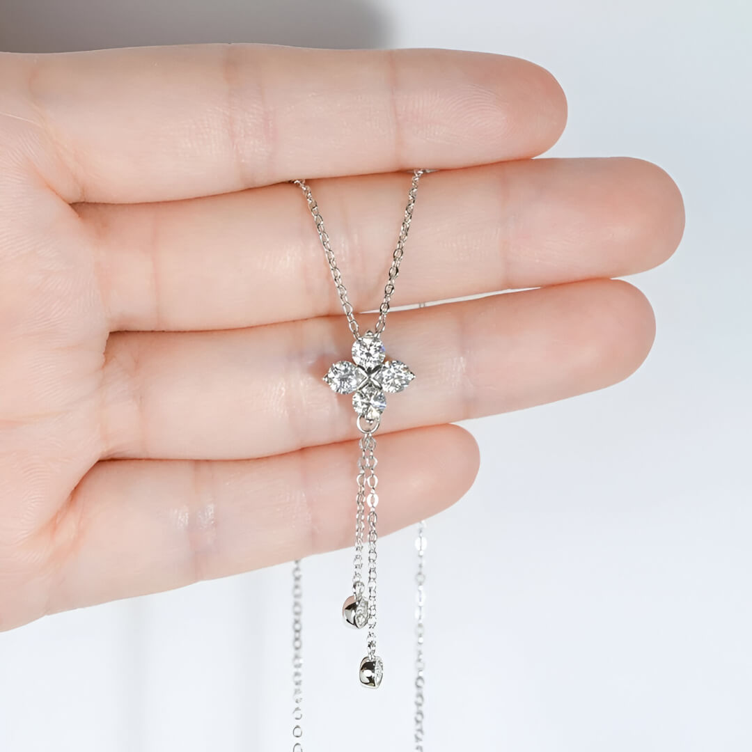 Pendentif fleur à pampilles en or blanc et diamants synthétiques dans une main vue de face.