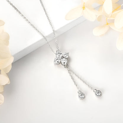 Pendentif fleur à pampilles en or blanc et diamants synthétiques posé.