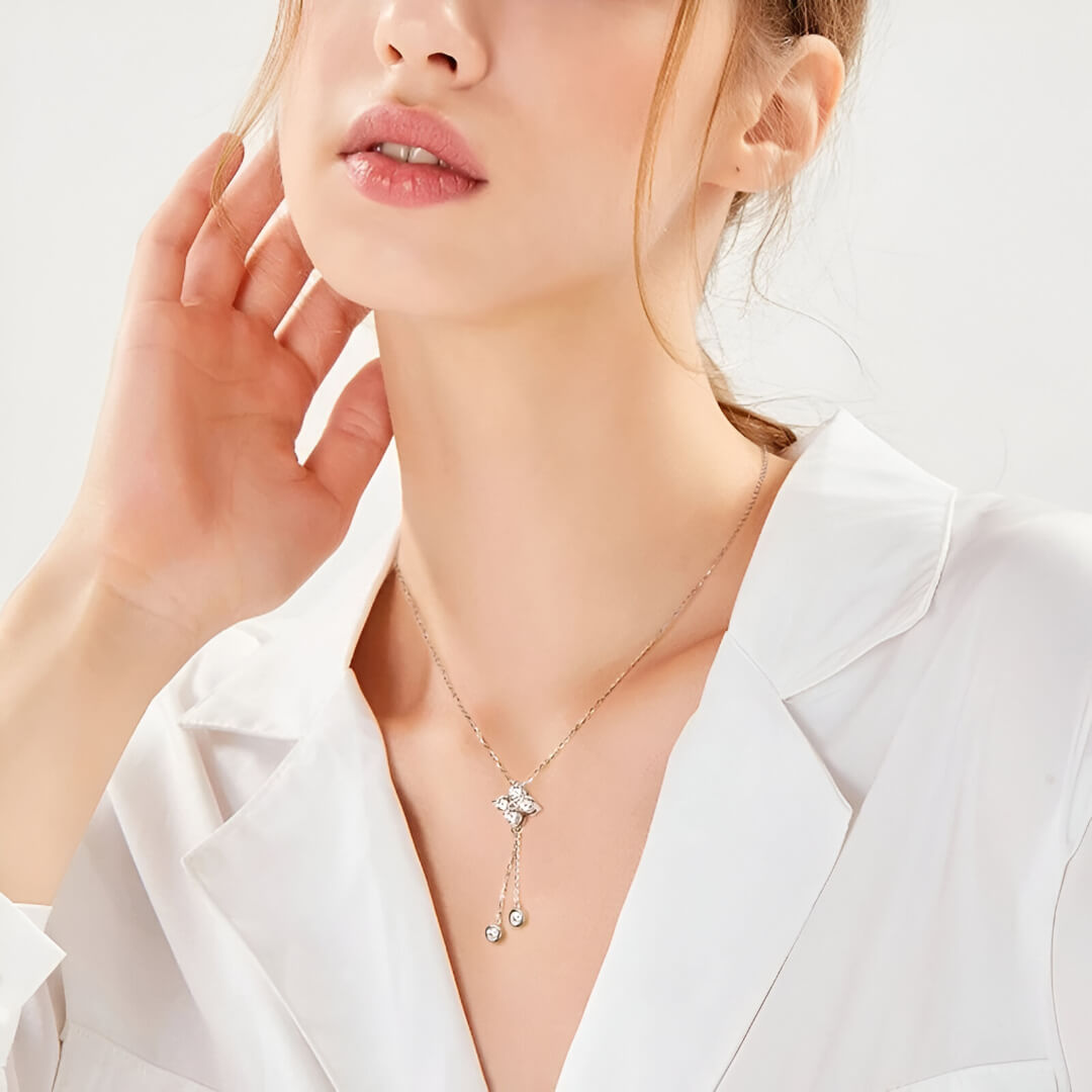 Pendentif fleur à pendeloques en argent sterling 925 plaqué or blanc et moissanites porté au cou d'une femme vue de loin.