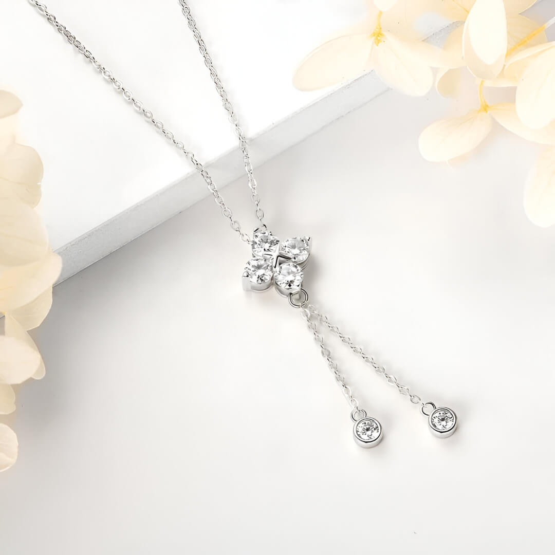 Pendentif fleur à pendeloques en argent 925 plaqué or blanc et moissanites scintillantes posé sur une surface blanche.