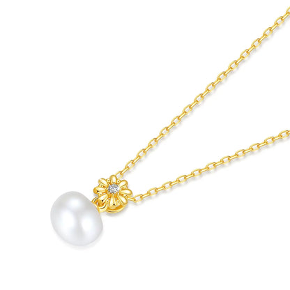 Pendentif fleur de marguerite Solénia en or jaune 18K lumineux orné d'un diamant et d'une perle naturelle vue de proche.