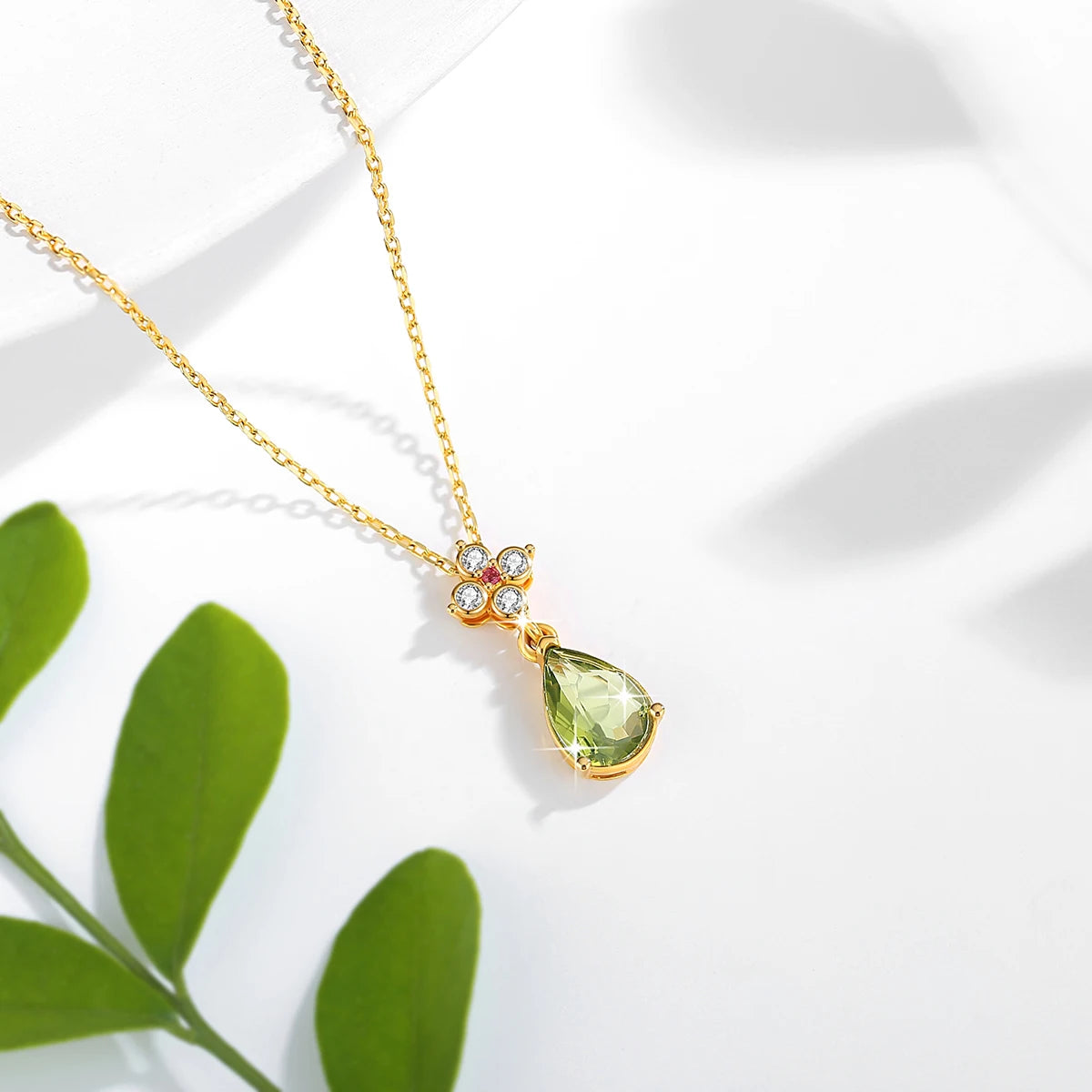 Pendentif goutte péridot Alexia en or jaune 18K orné d'un rubis et de diamants scintillants vue du dessus.