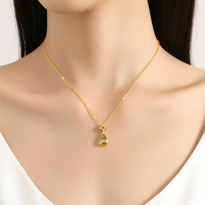 Pendentif goutte péridot en or jaune, rubis et diamants naturels porté au cou d'une femme.