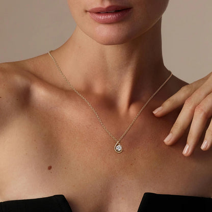 Pendentif goutte solitaire Océane en or jaune 14K et diamant rond éclatant serti trois griffes porté au cou d'une femme vue de loin.