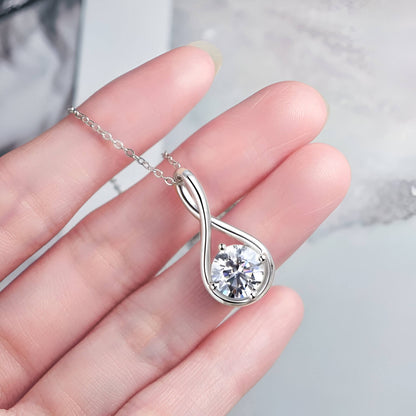 Pendentif goutte solitaire en or blanc et diamant synthétique sur une main vue du dessus.