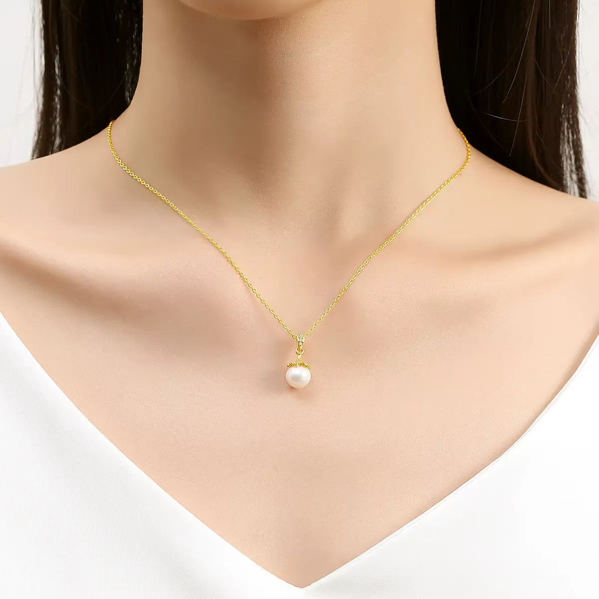 Pendentif lampe perlé en or jaune et diamants synthétiques porté au cou d'une femme.