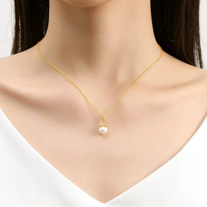 Pendentif lampe royale perle ronde Lumos en or jaune 18K et diamants éclatants porté au cou d'une femme vue de face.