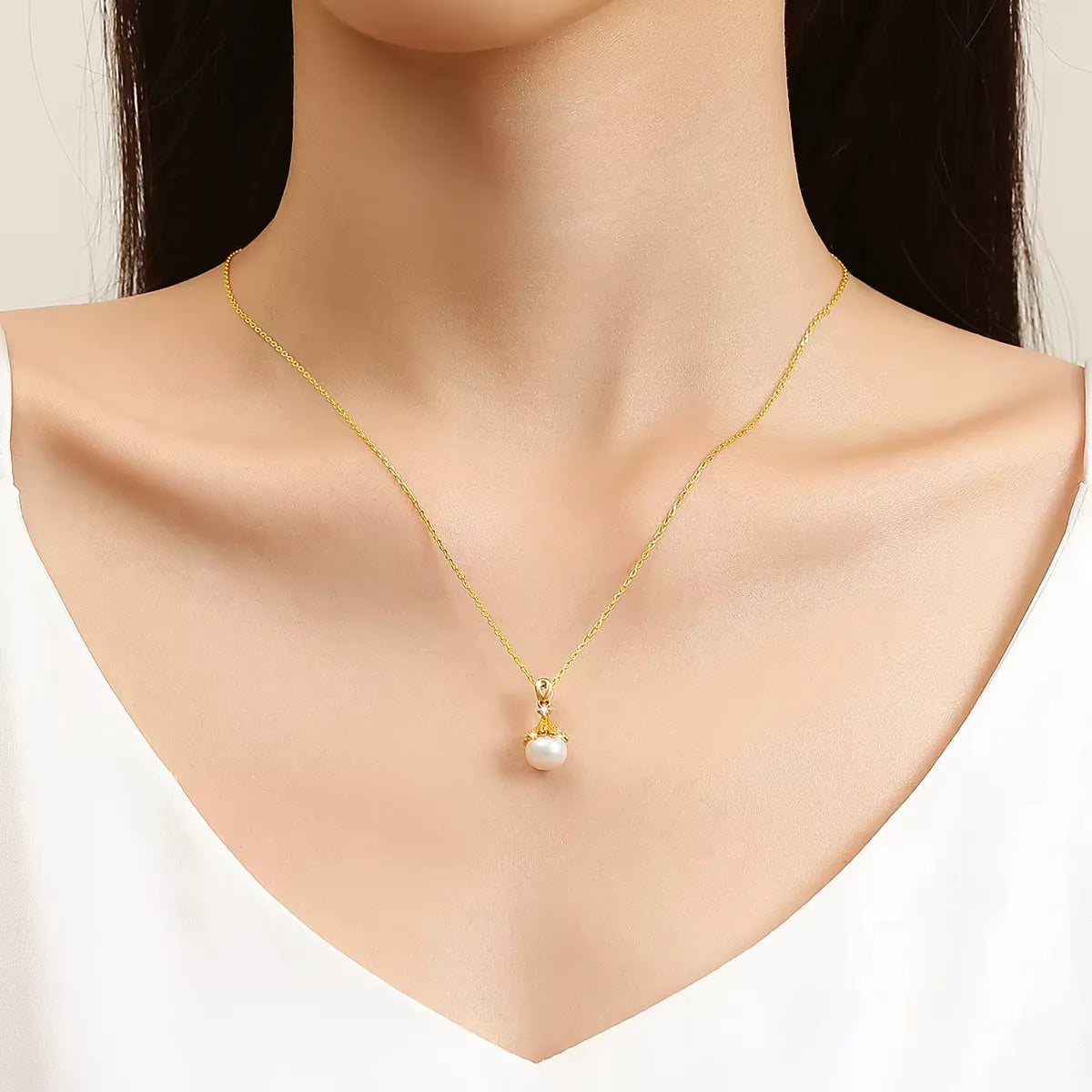 Pendentif lampe souveraine perle ovale Lumina en or jaune 18K raffiné et diamants porté au cou d'une femme vue de loin.
