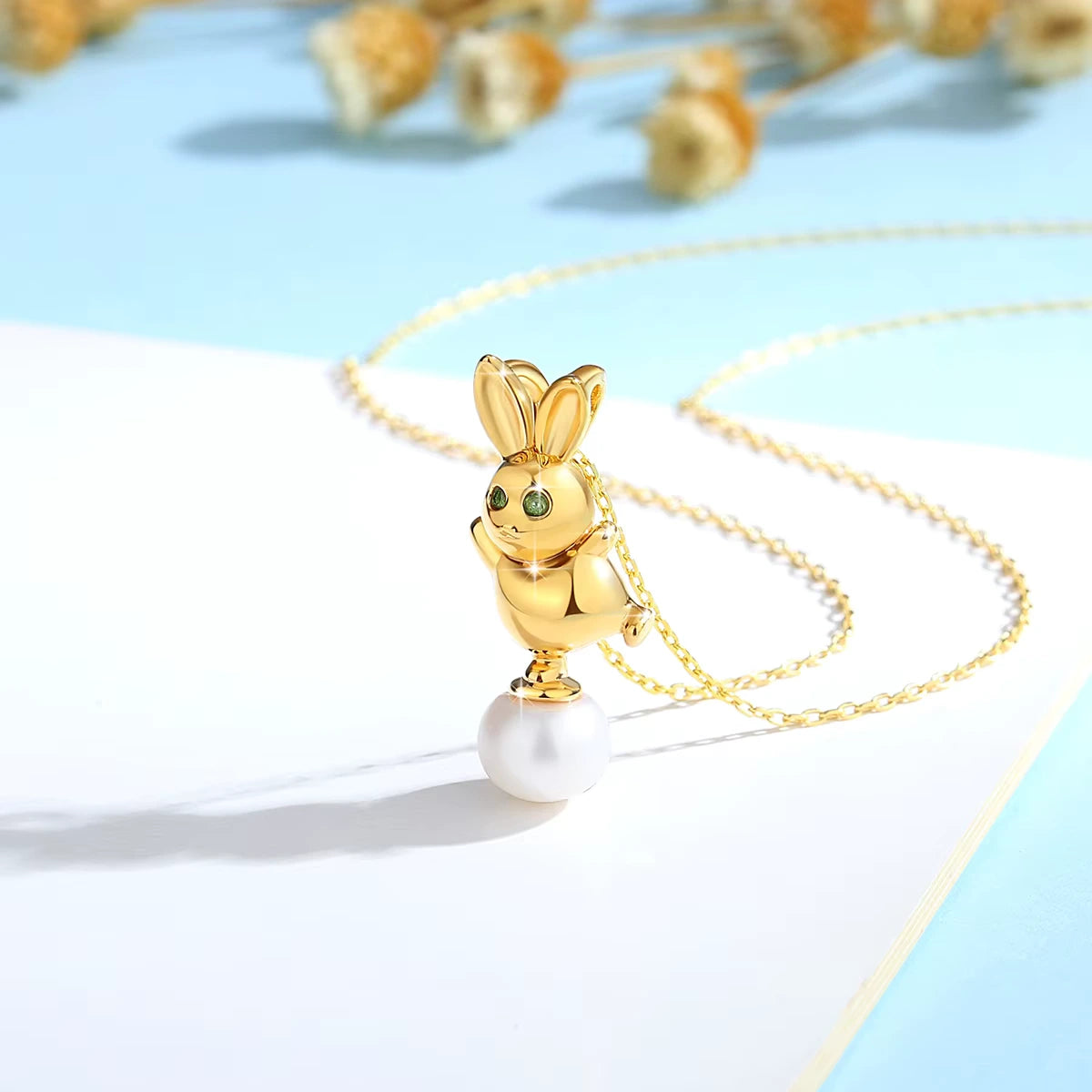 Pendentif lapin Bunny en or jaune 18K   resplendissant orné d'une perle ovale et de péridots verts vue de côté.