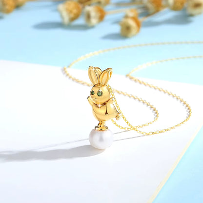 Pendentif lapin Bunny en or jaune 18K   resplendissant orné d'une perle ovale et de péridots verts vue de côté.