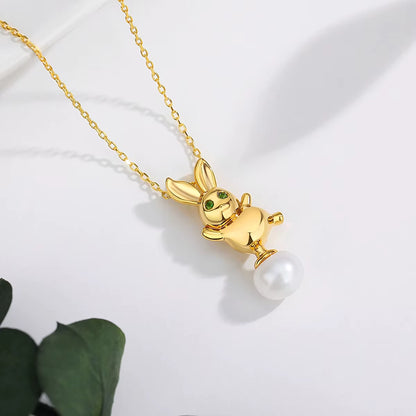 Pendentif lapin Bunny en or jaune 18K orné d'une perle ovale et de péridots verts éclatants à plat.