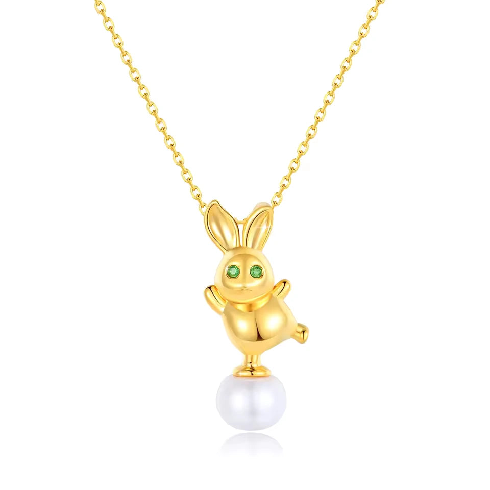 Pendentif lapin Bunny en or jaune 18K orné d'une perle ovale et de péridots verts sur fond blanc.