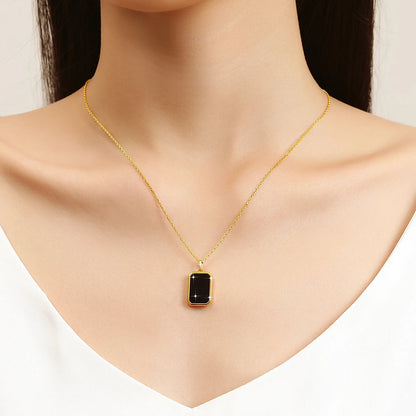 Pendentif médaillon rectangulaire en or jaune et onyx noir porté au cou d'une femme.