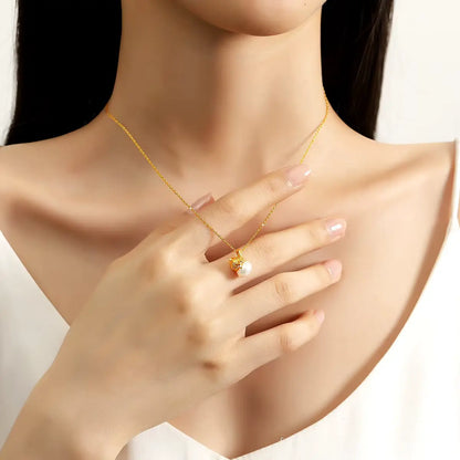 Pendentif nœud papillon Bonita en or jaune 18K et perle naturelle porté au cou d'une femme vue de loin.