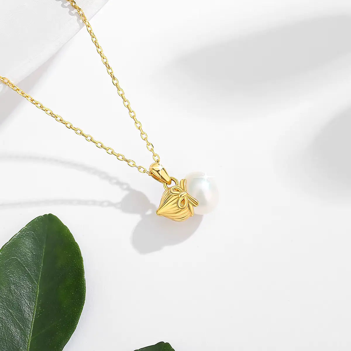 Pendentif nœud papillon en or jaune et perle vue du dessus.