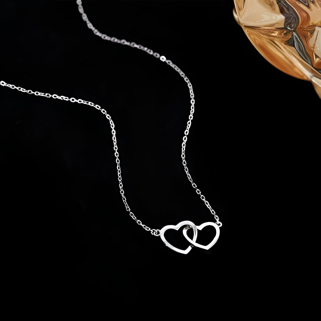 Collier pendentif fantaisie paire de cœurs en acier plaqué or blanc à plat.