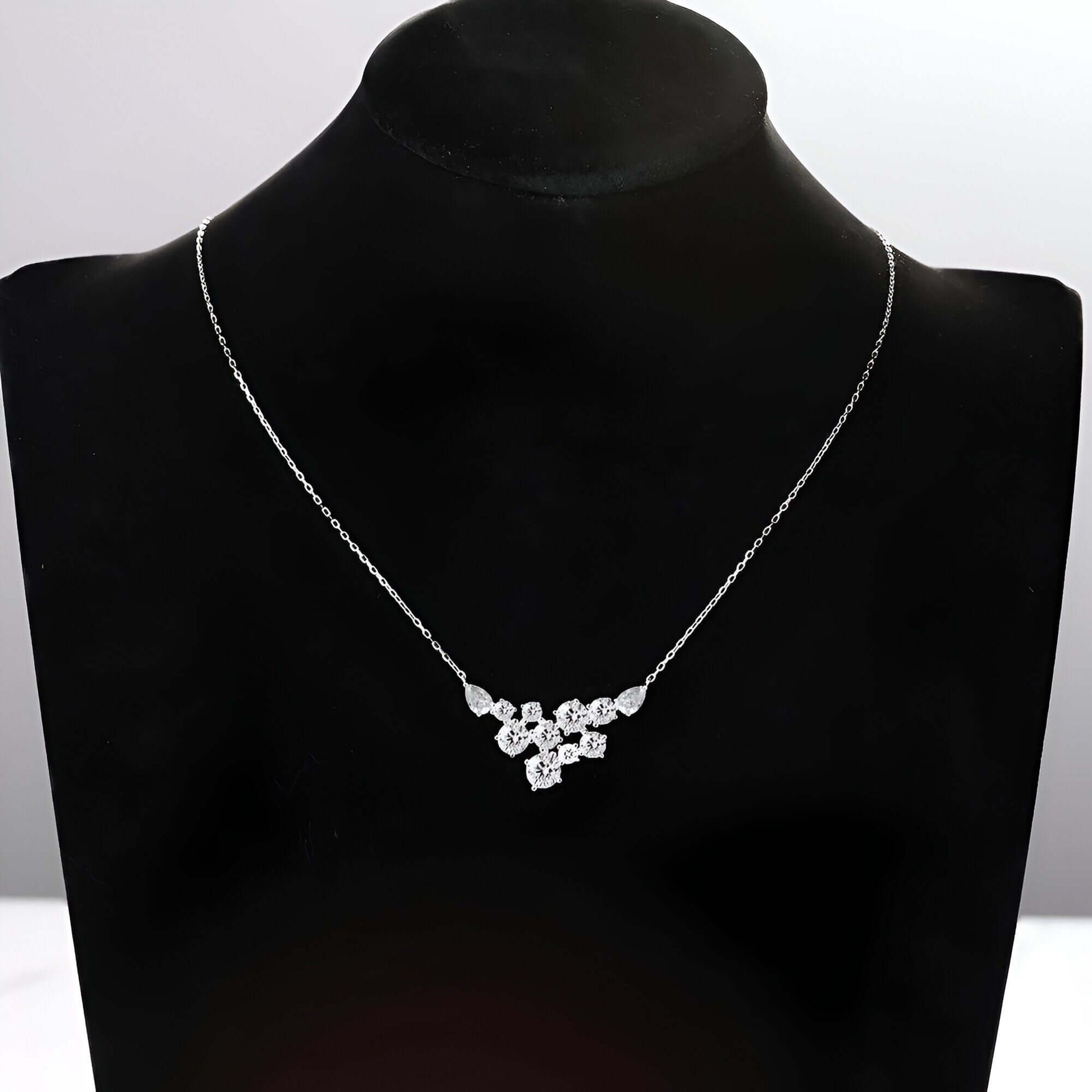 Pendentif pavé de diamants synthétiques en or blanc porté par un mannequin.