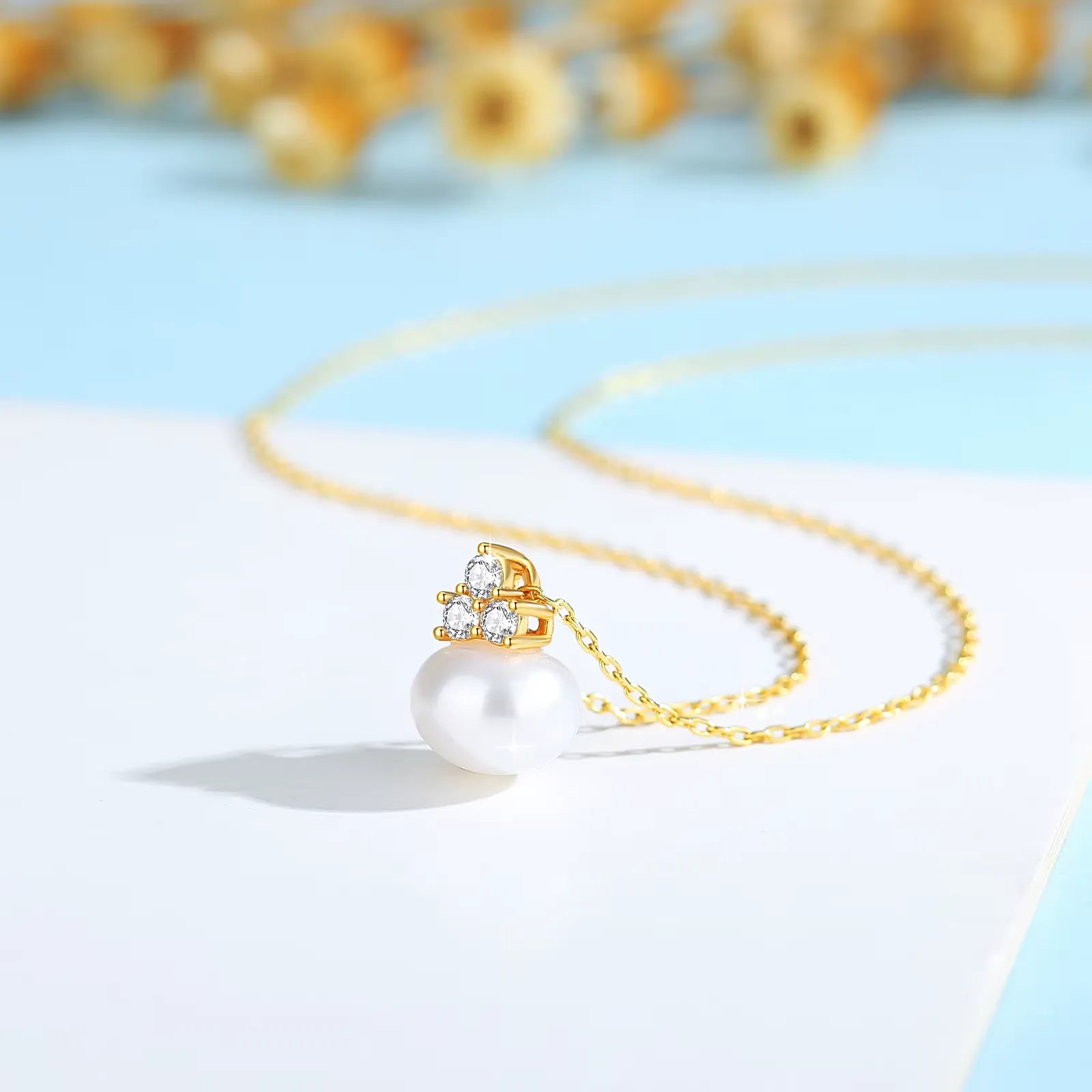 Pendentif perle solitaire en or jaune et trio de diamants synthétiques debout.