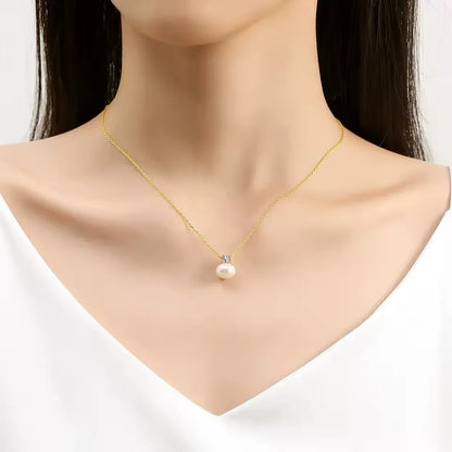 Pendentif perle solitaire nacrée Marie en or jaune 18K et diamant scintillant serti griffes porté au cou d'une femme vue de loin.