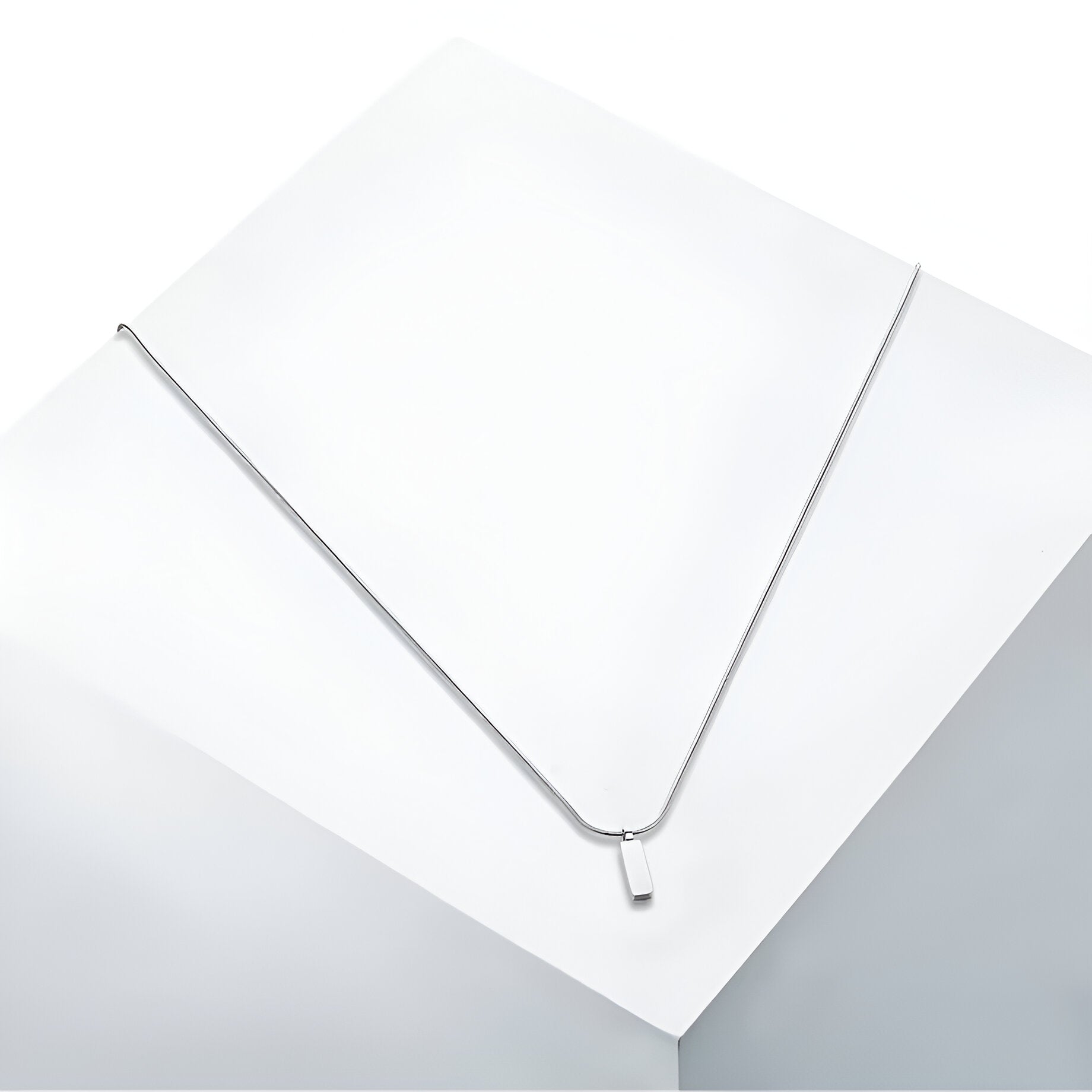 Pendentif rectangulaire en acier inoxydable et or blanc vue en gros plan.