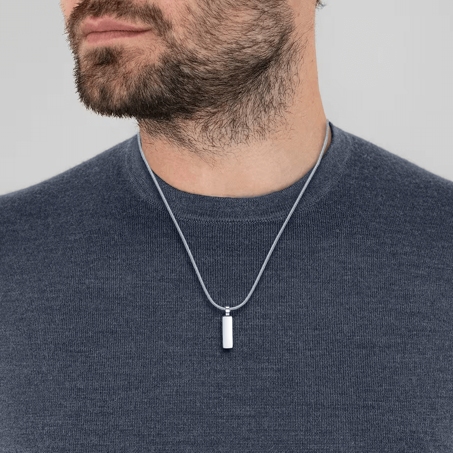 Pendentif rectangulaire en acier inoxydable et or blanc porté au cou d'un homme.