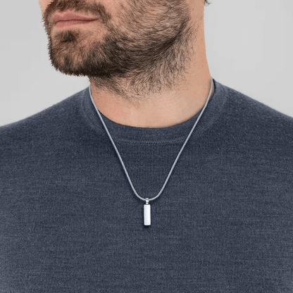Pendentif rectangulaire en acier inoxydable et or blanc porté au cou d'un homme.