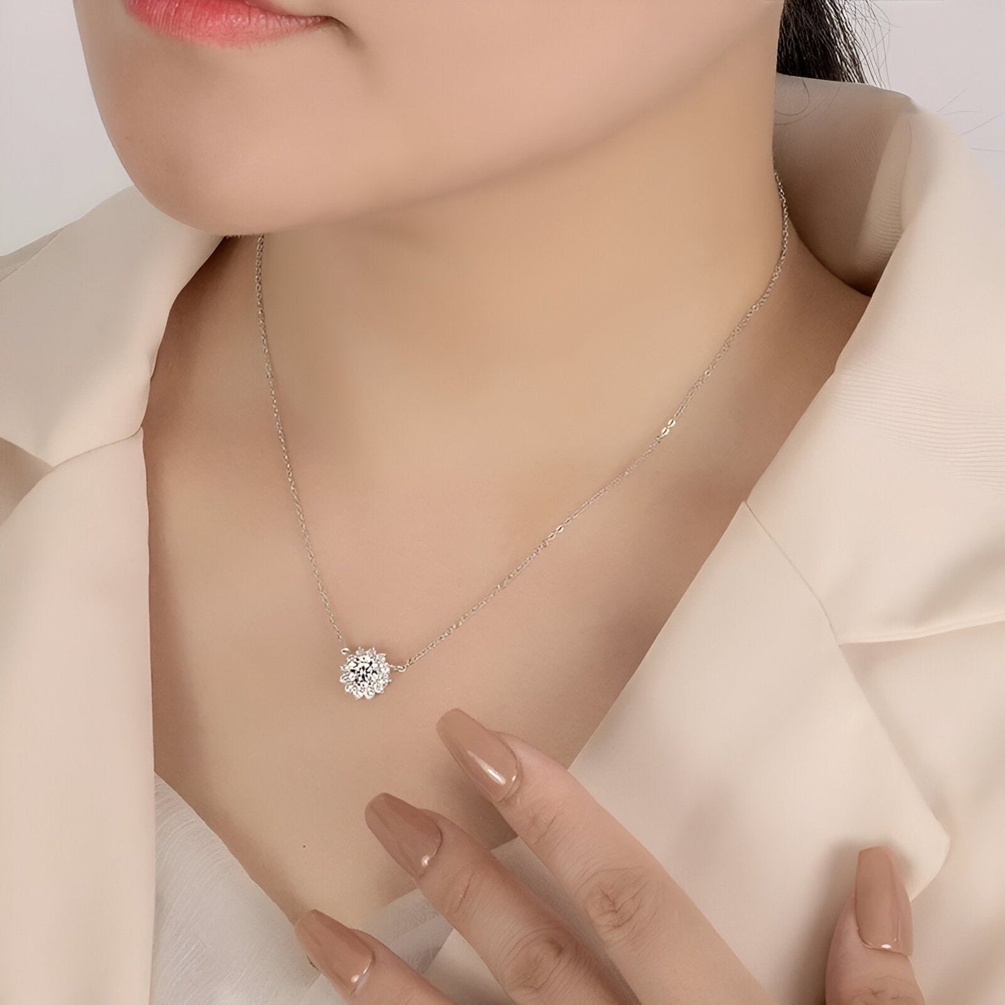 Pendentif solaire en or blanc et diamants synthétiques porté au cou d'une femme.