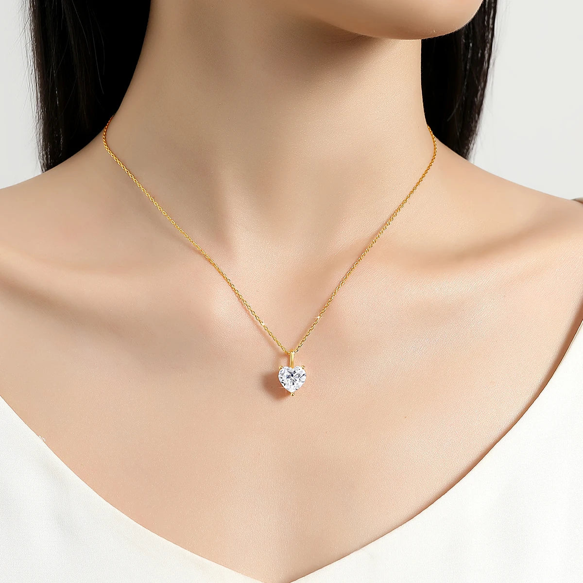Pendentif solitaire cœur en or jaune et diamant synthétique porté au cou d'une femme.