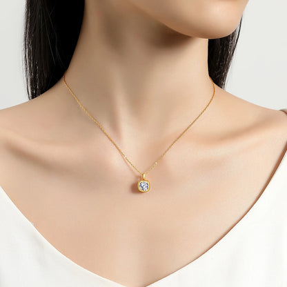 Pendentif solitaire cubique en or jaune et diamant synthétique porté au cou d'une femme.
