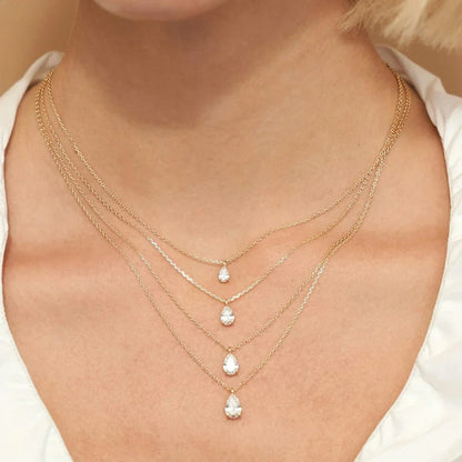 Variantes 0.5CT, 1CT et 2CT du collier pendentif solitaire diamant goutte serti trois griffes Emelynn en or jaune 14K portées au cou d'une femme.