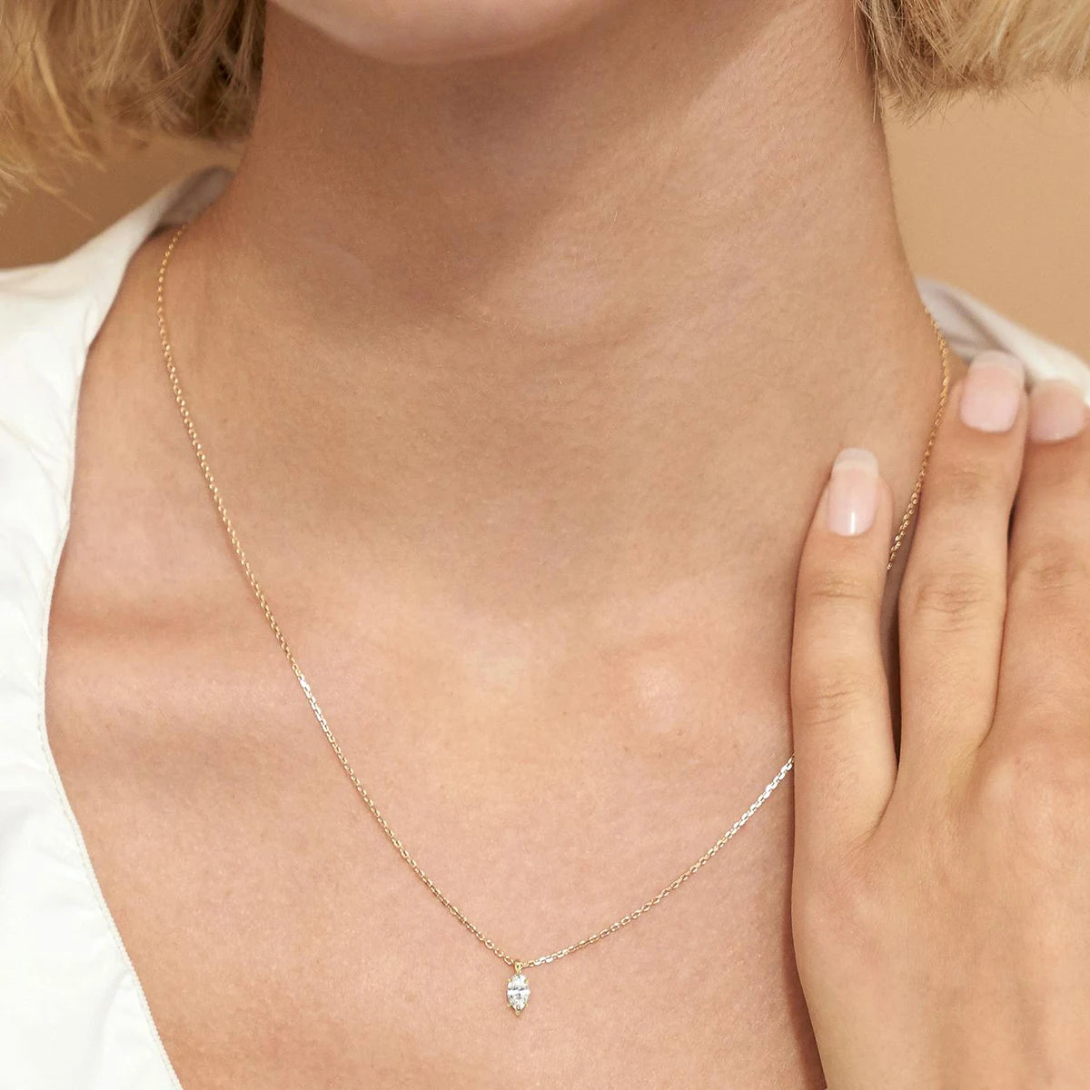 Pendentif solitaire diamant marquis scintillant serti six griffes Yrelia en or jaune 14K porté au cou d'une femme vue de loin.
