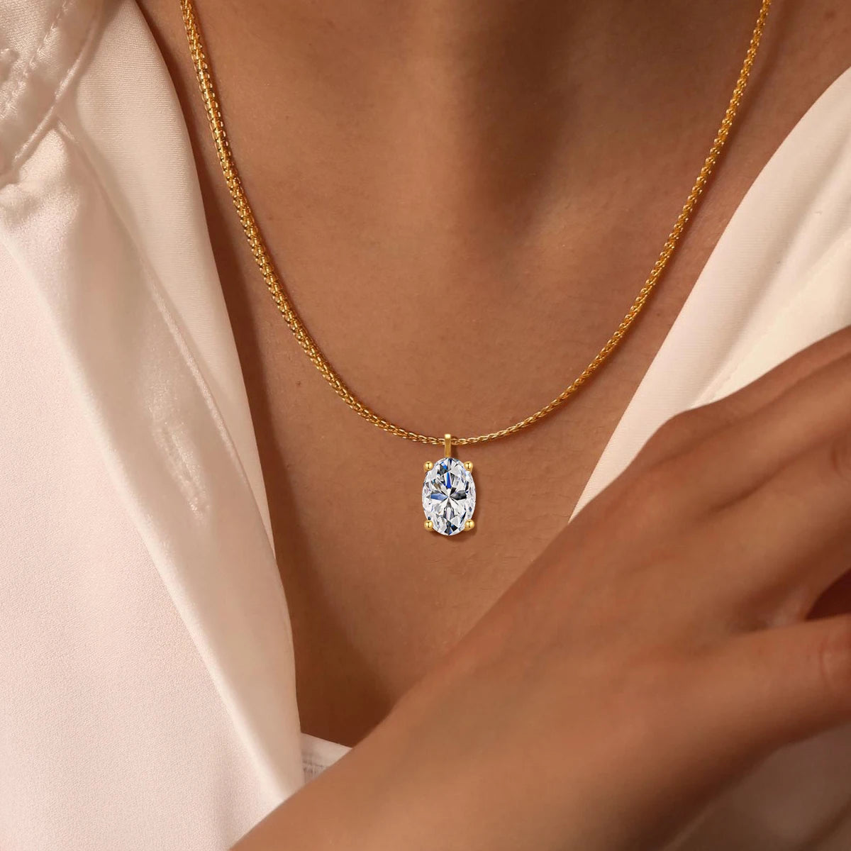 Pendentif solitaire diamant ovale serti quatre griffes Maelys en or jaune 14K raffiné porté au cou d'une femme vue de proche.
