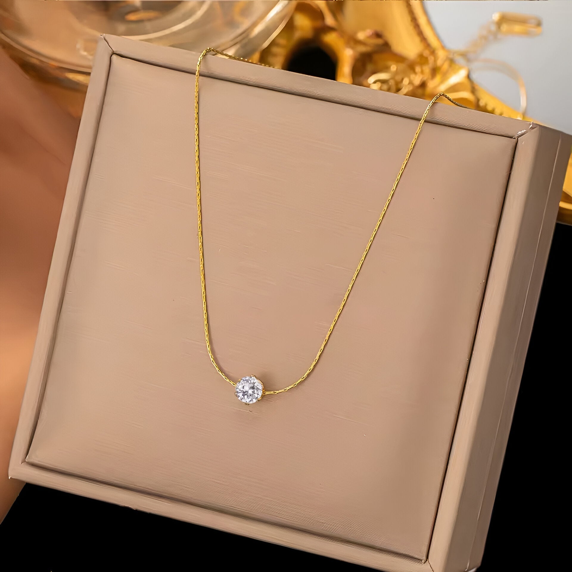 Pendentif solitaire en acier doré et diamant naturel sur un écrin.