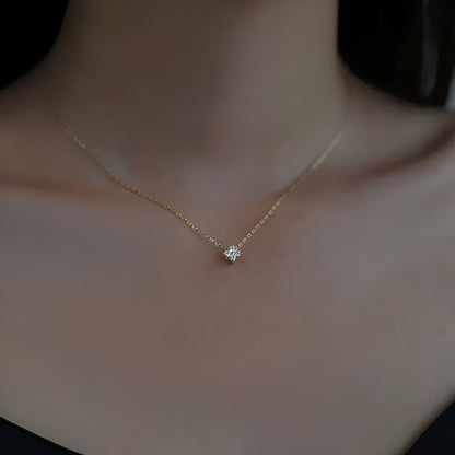 Pendentif solitaire en or jaune et diamants synthétiques porté au cou d'une femme.
