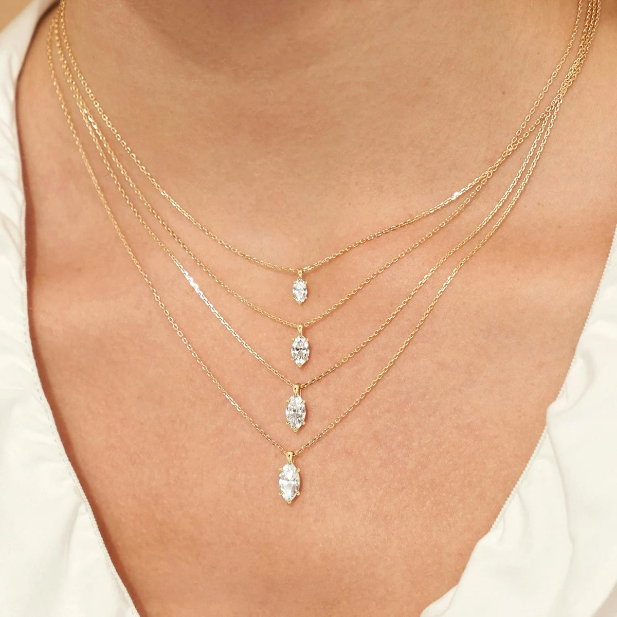 Pendentifs solitaire marquis en or jaune et diamant synthétique 1 carat, 2 carats et 3 carats portés au cou d'une femme.