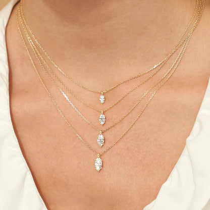 Pendentifs solitaire marquis en or jaune et diamant synthétique 1 carat, 2 carats et 3 carats portés au cou d'une femme.