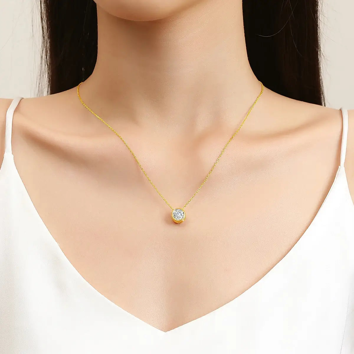 Pendentif solitaire Naélie en or jaune 18K et diamant rond porté au cou d'une femme vue de face.