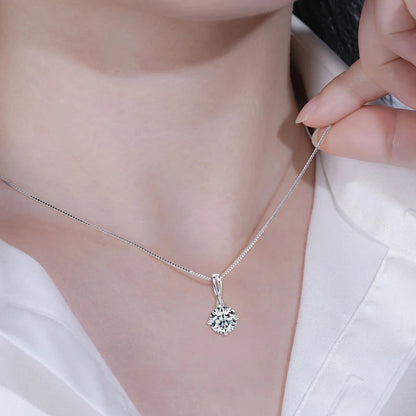 Pendentif solitaire en or blanc et diamant synthétique porté au cou d'une femme.