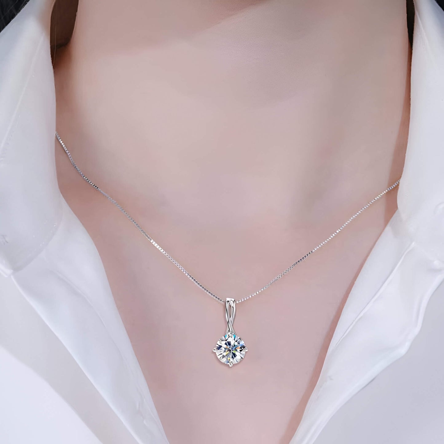 Pendentif solitaire en or blanc et diamant synthétique porté au cou d'une femme vue de face.