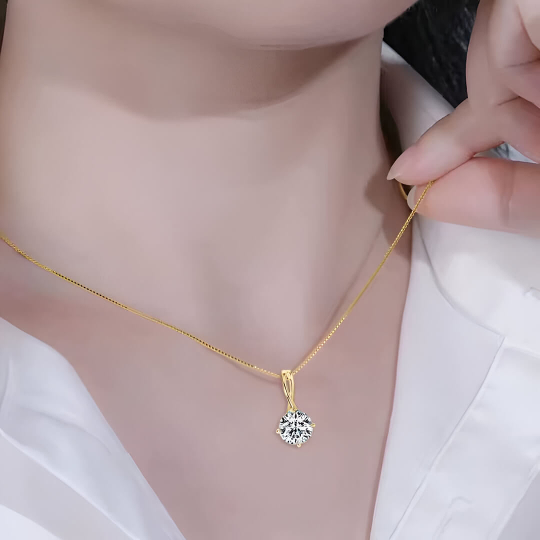 Pendentif solitaire en or jaune et diamant synthétique porté au cou d'une femme.