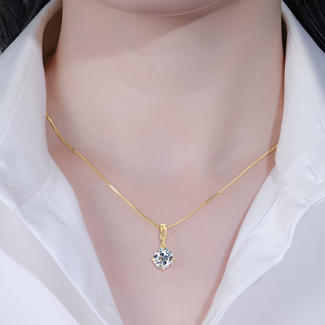 Pendentif solitaire en or jaune et diamant synthétique porté au cou d'une femme vue de face.