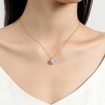 Pendentif solitaire rond en or jaune et diamant synthétique porté au cou d'une femme.
