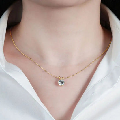 Pendentif solitaire serti six griffes en argent 925 plaqué or jaune et diamant 4ct éclatant porté au cou d'une femme vue de proche.