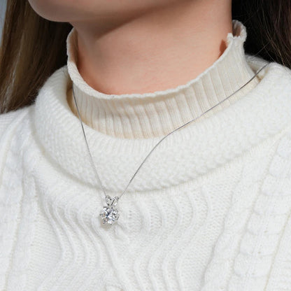 Collier pendentif solitaire en or blanc et diamant synthétique porté au cou d'une femme vue de proche.