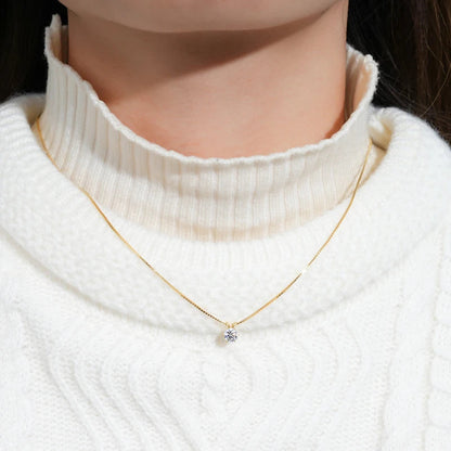 Collier pendentif solitaire en or jaune et diamant synthétique porté au cou d'une femme vue de face.