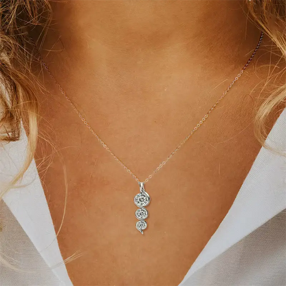 Pendentif torsadé en or blanc et diamants synthétiques porté au cou d'une femme vue de face.