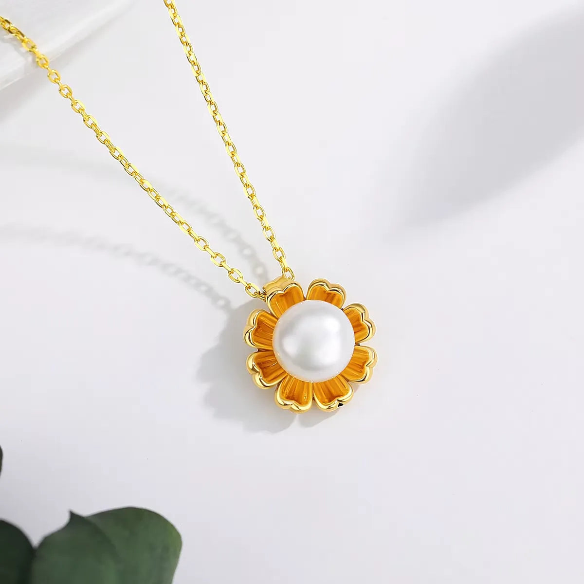 Pendentif fleur de tournesol en or jaune et perle nacrée vue du dessus.